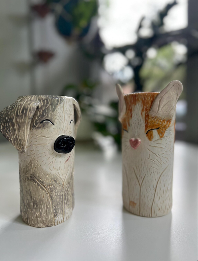 A ceramic dog vase and cat vase side by side